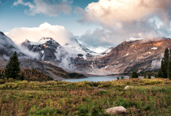 montagna innevata vicino lago e prato verde